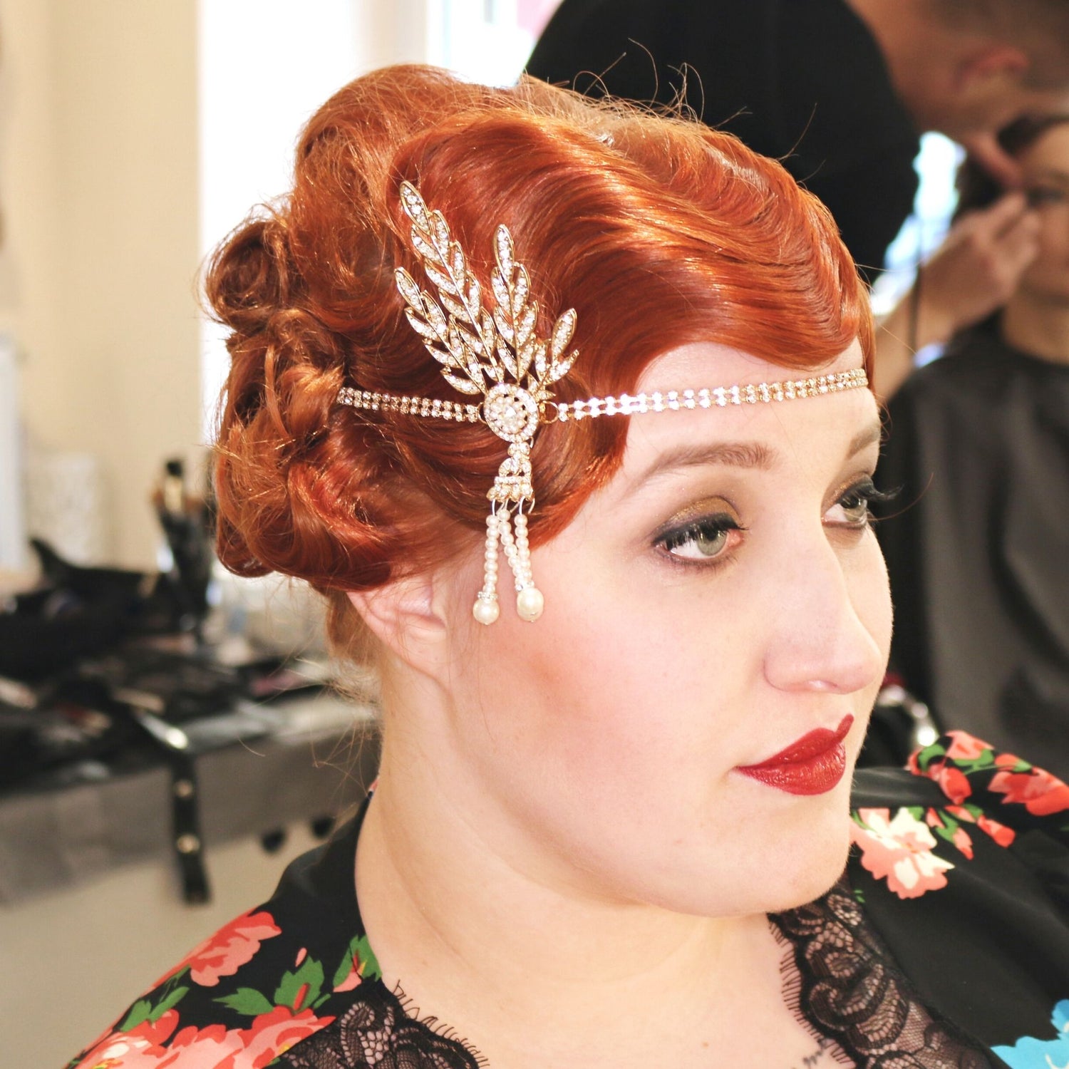 Eine Frau sitzt bei der Stylistin Silke Kamchen mit ihrer frisch gelegten Wasserwelle. Sie möchte die Boheme Sauvage besuchen und trägt zu ihrem kupferfarbenem Haar den perfekten Lippenstift. Sie sieht einfach umwerfend aus.